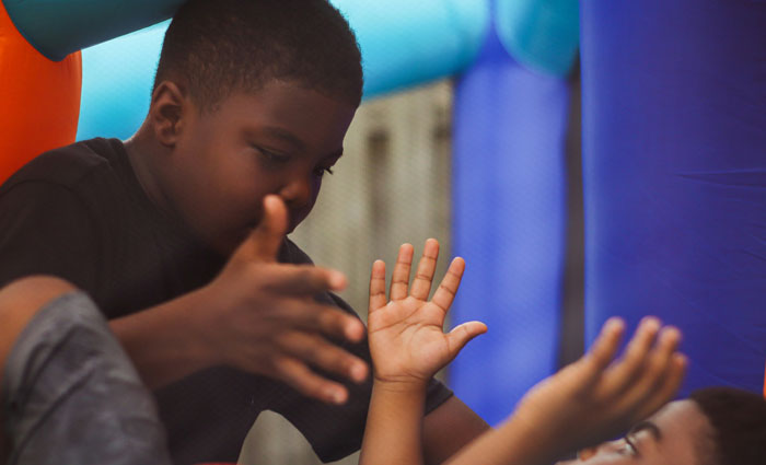 Two kids playfully gesturing inside a colorful inflatable, capturing a humorous moment shared by teachers.