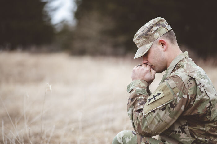 Soldier in uniform kneeling in a field, representing unique USA cultural aspects.