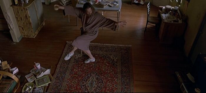 Person in robe and sneakers striking a pose on a rug in a cluttered room, related to famous movie props stories.