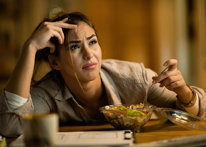 Woman eating salad with a puzzled expression, related to a decoy lunch scenario.