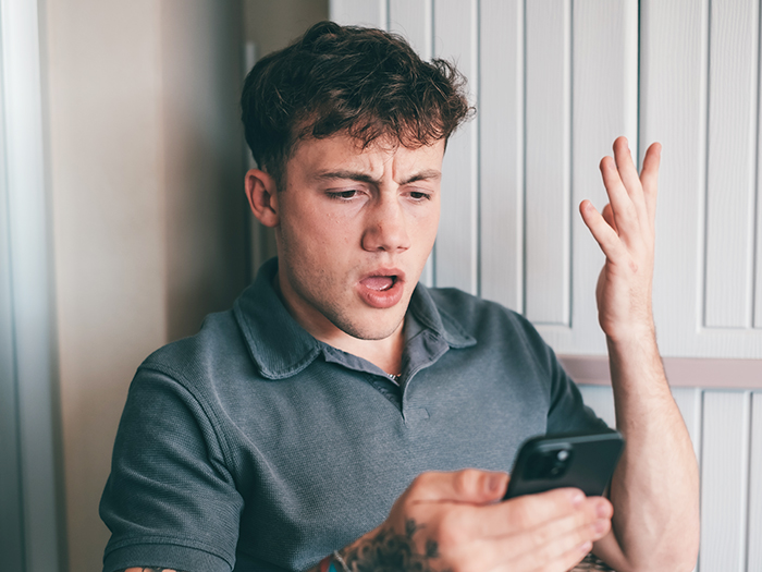 Teen looking surprised at phone, referencing fake account creation to influence religious parents' views on brother's sexuality.