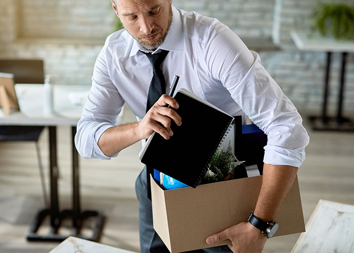 Man packing office items into a box, symbolizing revenge against bosses.