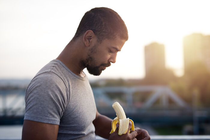 Man peeling a banana outdoors at sunset, illustrating common stereotypes about what real men don't do.
