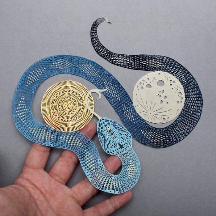 Intricate paper art design featuring a detailed blue snake, showcasing nature-inspired patterns by Pippa Dyrlaga.