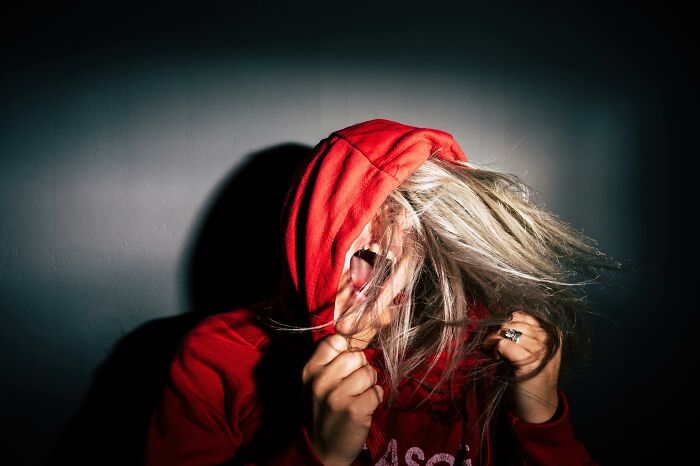 Individual in red hoodie with hair covering face, symbolizing change in mindsets.