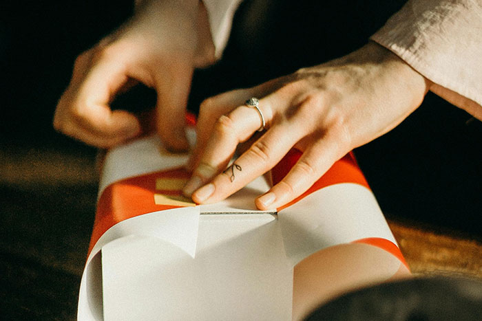 Hands wrapping a gift, representing safe side hustle ideas with creativity and care.