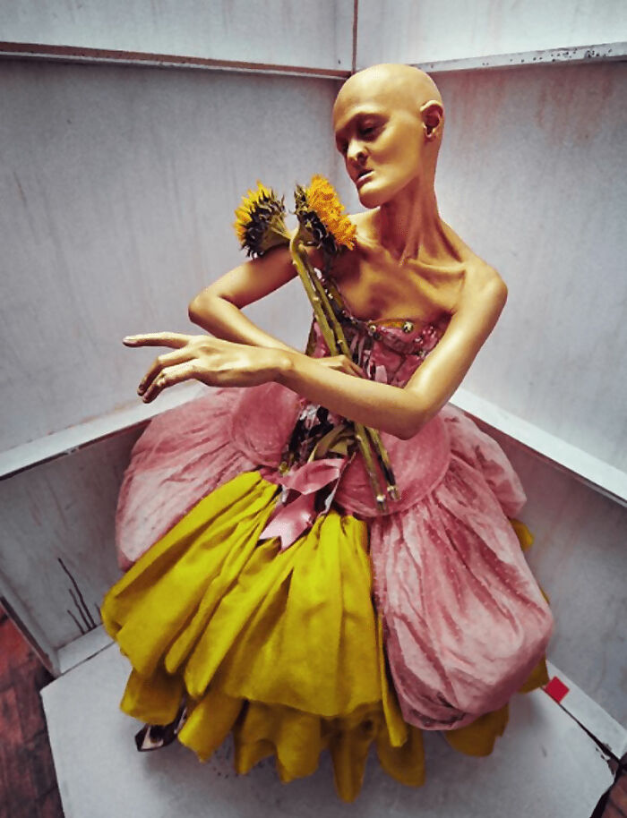 Unique model posing with sunflowers in a colorful dress, showcasing artistic expression.