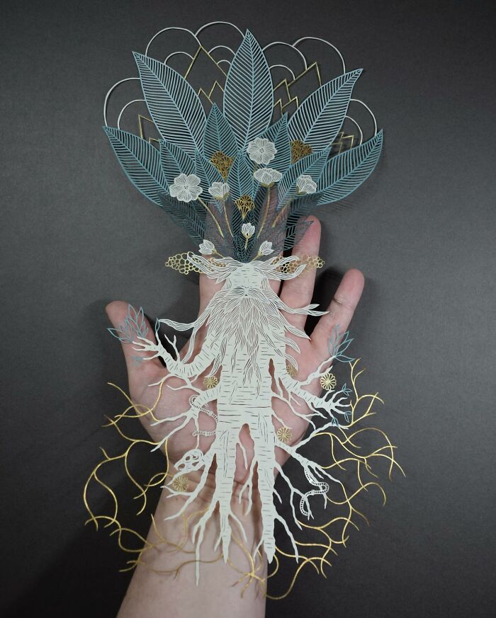 Intricate paper art design featuring nature-inspired patterns held in a hand.