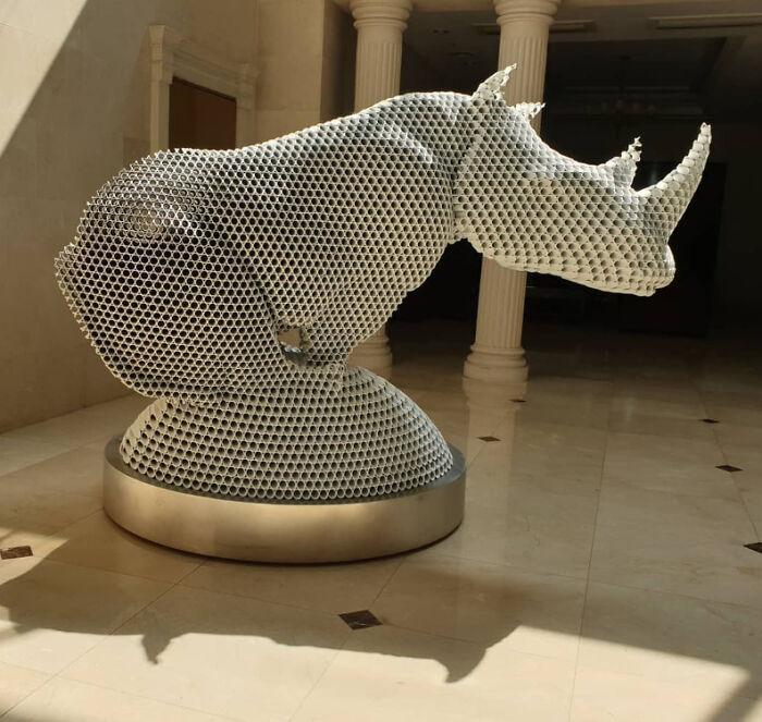 Metal pipe sculpture of a rhino by Yi Chul Hee, displayed in a sunlit room with marble flooring.