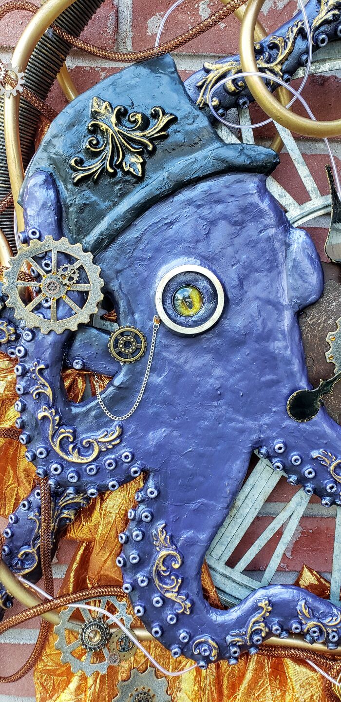 Steampunk octopus decoration with a top hat and gears, displaying intricate metalwork on a brick wall background.