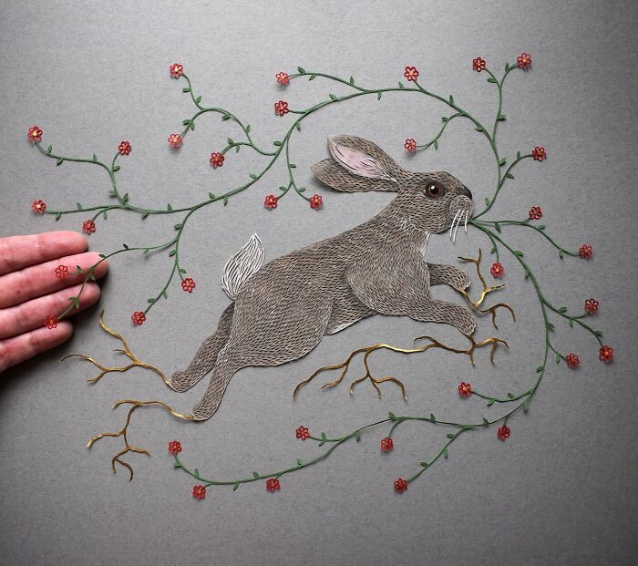 Intricate paper art of a rabbit surrounded by floral vines, showcasing nature-inspired design by Pippa Dyrlaga.