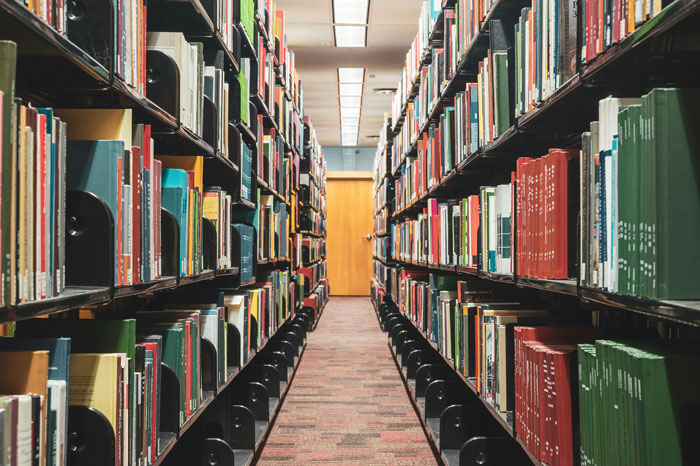 Library aisle with numerous books on shelves, symbolizing knowledge and rich experiences beyond reality.