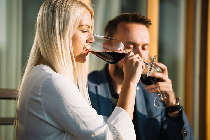 Couple on a first date sipping wine outdoors, both looking thoughtful.