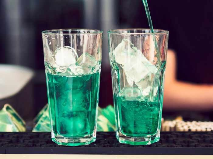 Two glasses filled with ice and bright green liquid, illustrating an American norm.