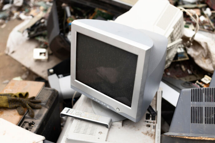 Old computer monitor and remote discarded among electronic waste, illustrating consequences of individual rules implementation.