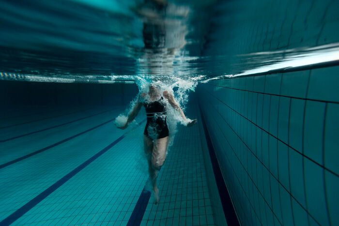 Person swimming underwater in a pool, creating bubbles, showcasing fascinating facts about the world.