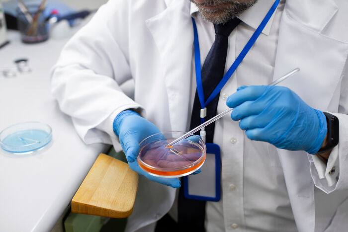 Scientist in lab coat examining a petri dish with a pipette, exploring fascinating facts about the world.