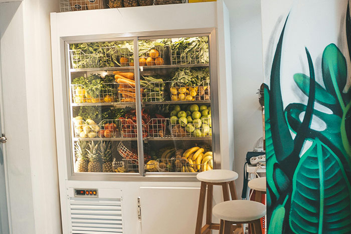 Fruit display in a café with various tropical fruits and plants, showcasing a vibrant and healthy side hustle idea.