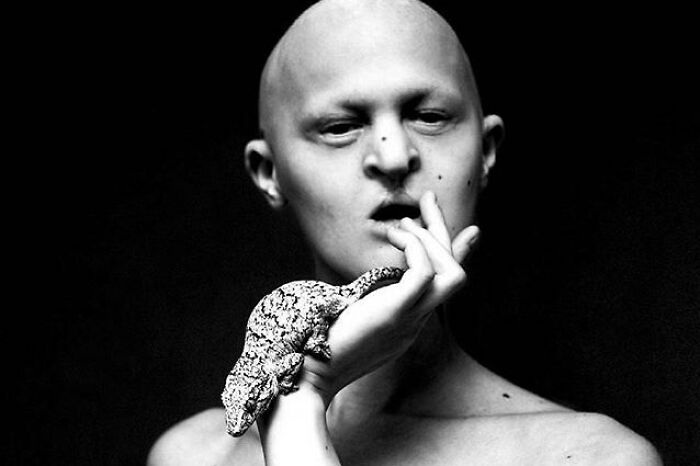 Unique model with a lizard on hand, expressing creativity in a black and white artistic portrait.