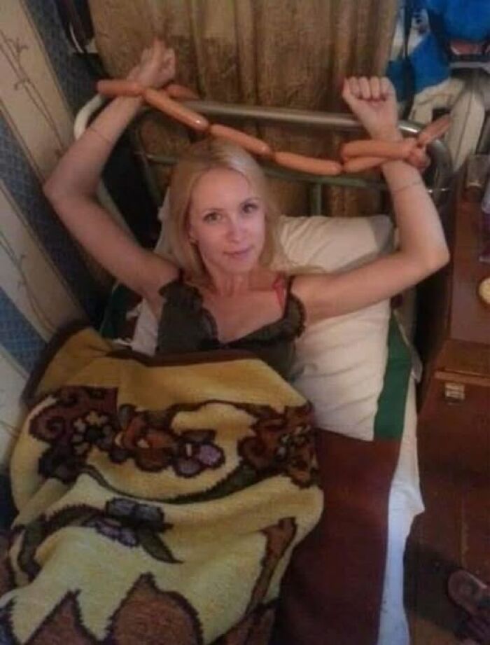 Woman in bed using sausages as handcuffs, showcasing a weird image in an amusing and unusual context.