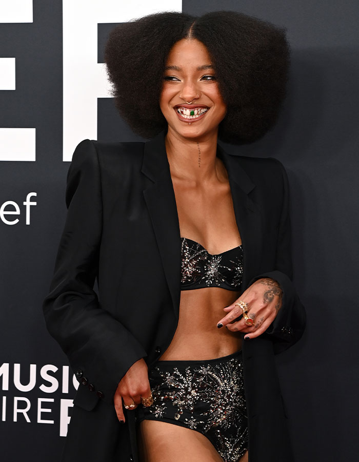 Individual in a black and silver outfit on the red carpet at the 2025 Grammys.