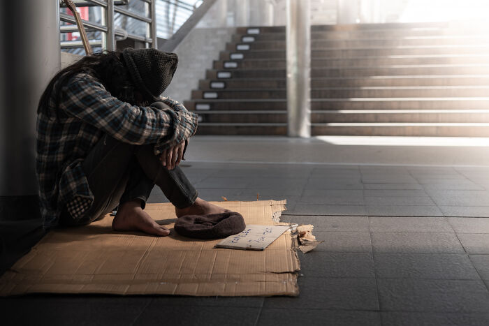 Person sitting on cardboard near stairs, highlighting non-physical qualities linked to attractiveness.