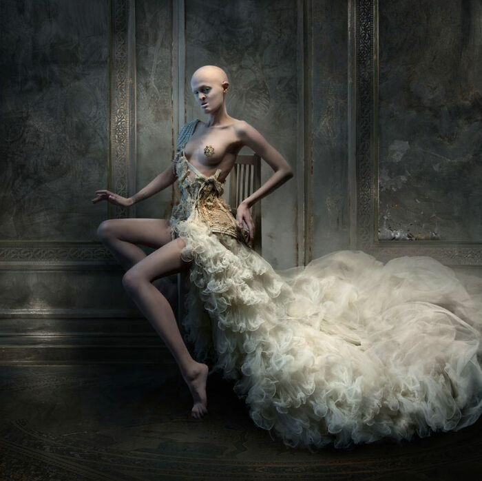 Unique model in an artistic dress posing in an ornate room setting.