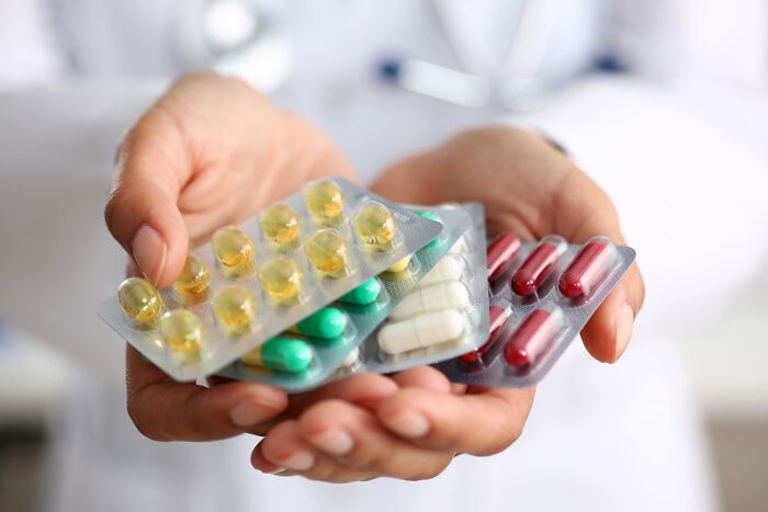 Hands holding blister packs of pills, illustrating American norms around medication accessibility.