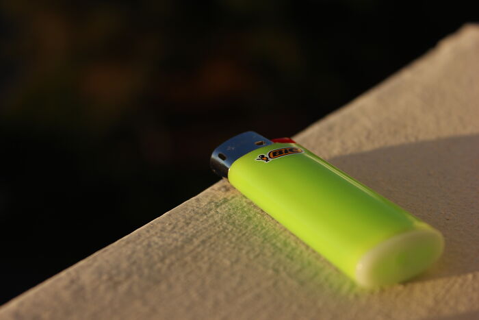 A durable, neon green lighter placed on a ledge, showcasing its simple, long-lasting design.