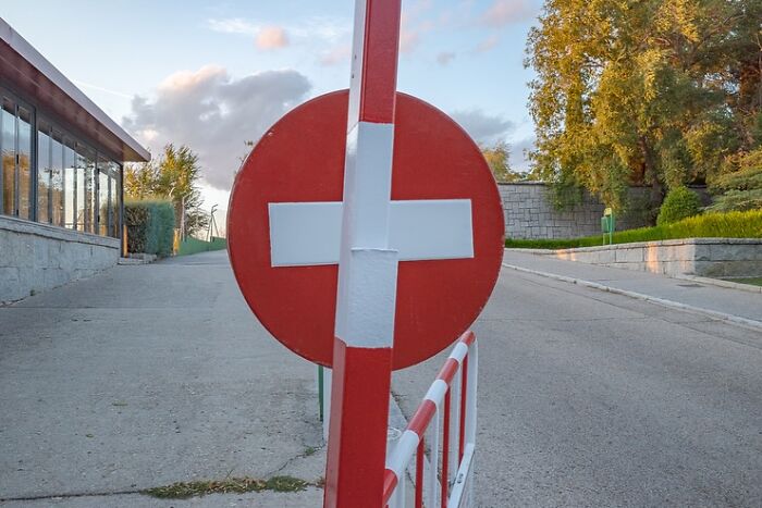 A red and white sign perfectly aligns with a barrier, creating a coincidence that appears visually seamless.