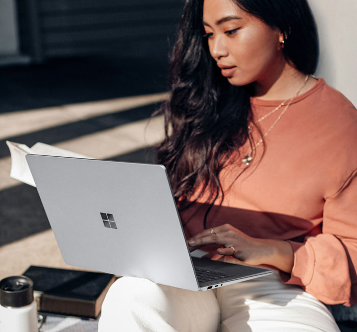 Woman researching background information on a laptop outdoors.