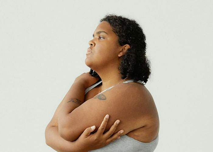 Person in a grey tank top looking thoughtful, illustrating challenges of being overweight.