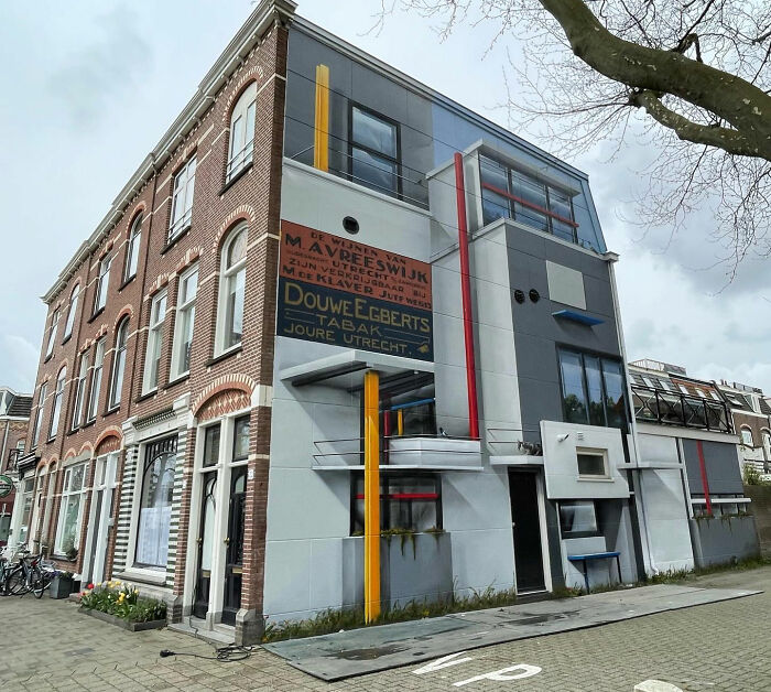 Hyperrealistic mural by Jan Is De Man on a city building wall, featuring geometric patterns and historical signage.