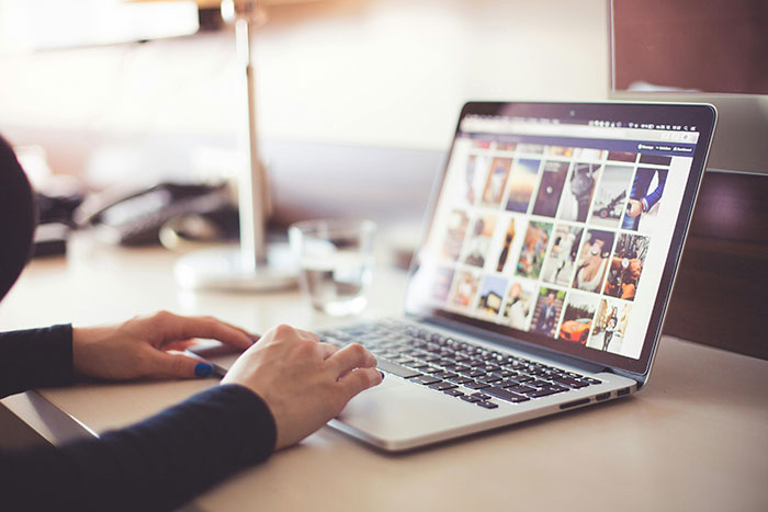 A woman using a laptop, exploring online for safe side hustle ideas.