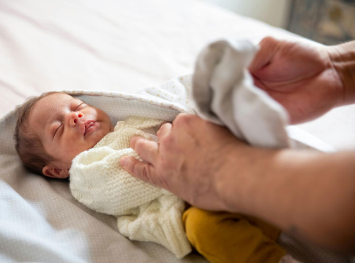 Newborn wrapped in a blanket on a bed, exemplifying how perceptions vary based on wealth.