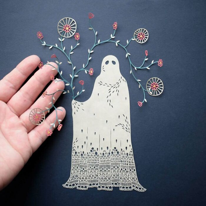 Nature-inspired intricate paper art design held by a hand featuring delicate floral patterns.