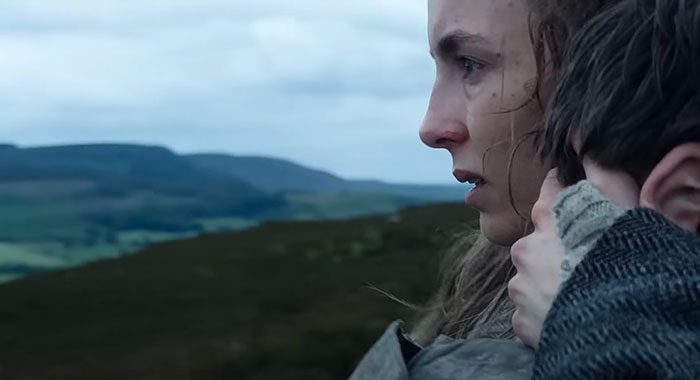 Woman in a countryside setting, part of the 28 Years Later cast, looking concerned while holding another person. Woman in a countryside setting, part of the 28 Years Later cast, looking concerned while holding another person.