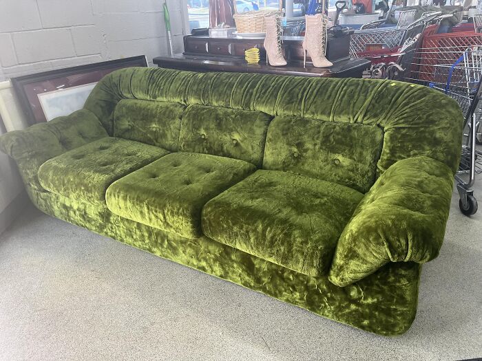 Vintage green velvet couch in a thrift store, representing financial decisions.