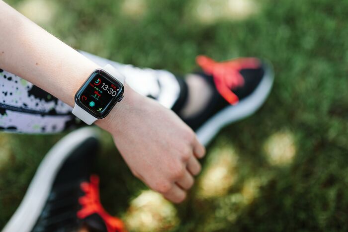 A person wearing a smartwatch and exercise shoes on grass, embodying fitness myths.