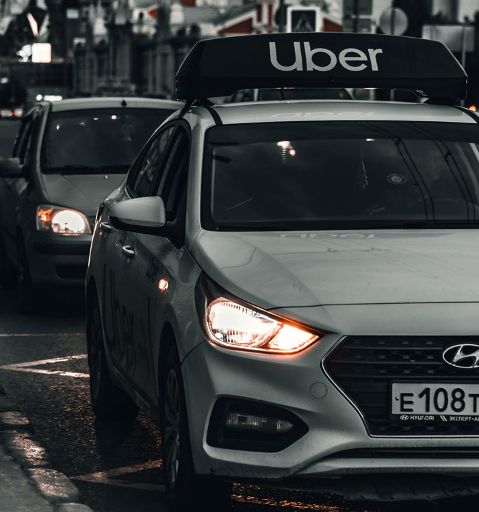 Coche con letrero de servicio Uber en la calle por la noche.