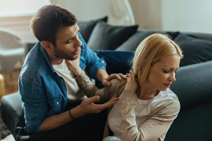 A man in a denim shirt and a woman in a beige cardigan having a serious conversation on a couch about dumb things said.