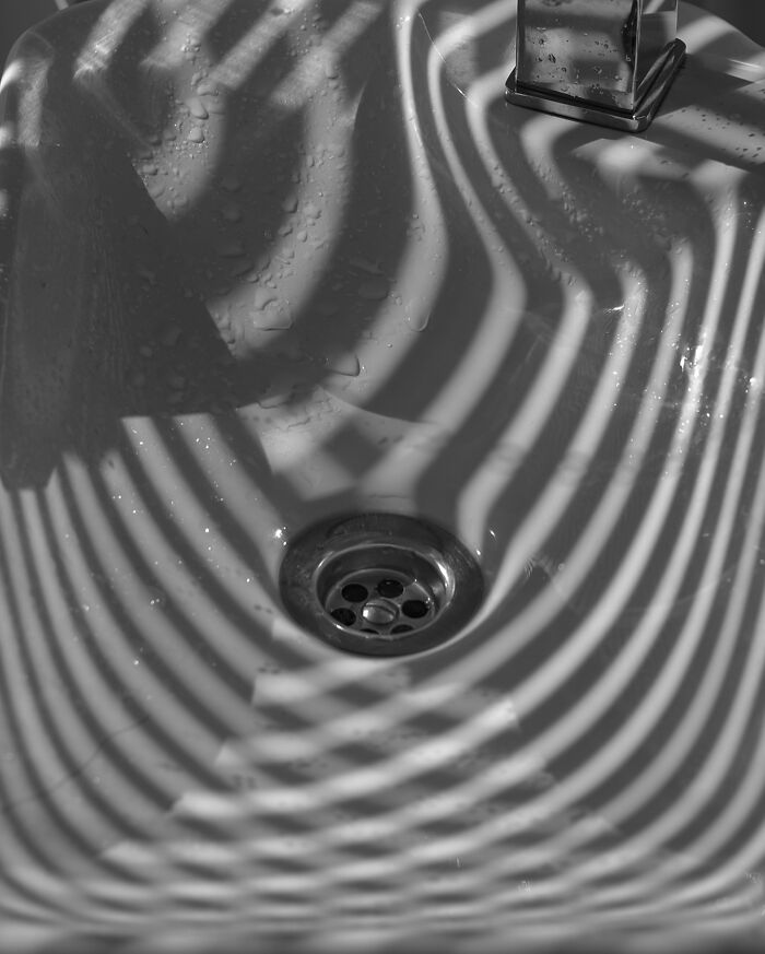 Shadows create wavy lines in a sink, showcasing coincidence photography with intriguing patterns.