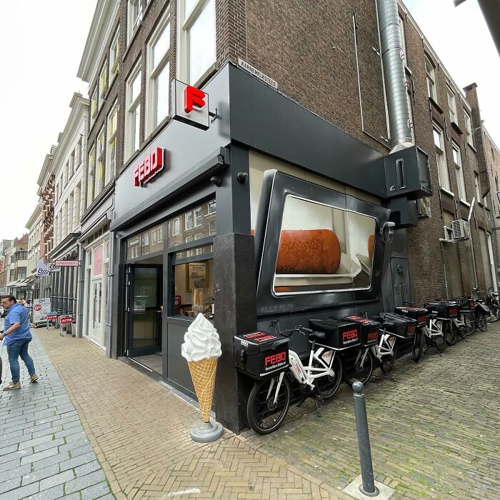 Hyperrealistic mural by Jan Is De Man on a city wall, depicting a food item in an oversized vending machine.