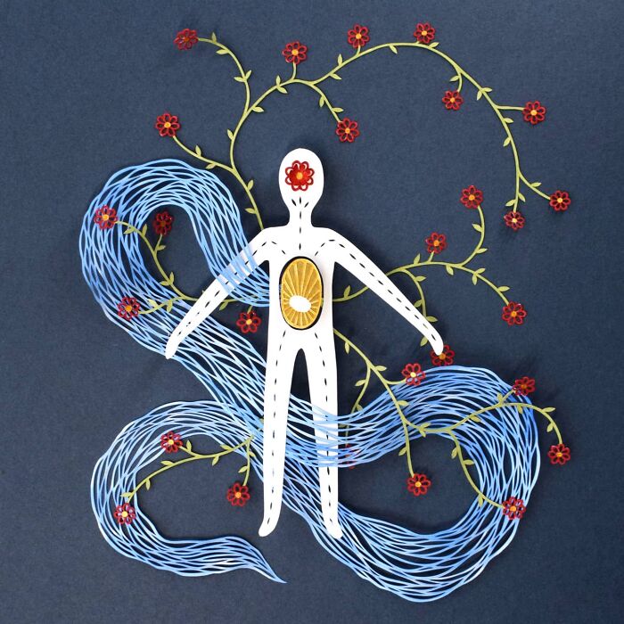 Intricate paper art design of a figure with swirling patterns and floral elements on a dark background.