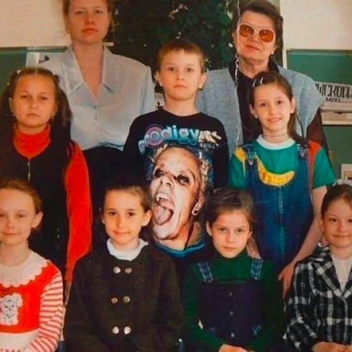 Grupo de niños y adultos posando, uno de los niños lleva una camiseta con diseño inusual, creando una imagen rara.