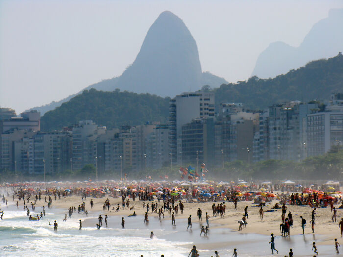 Retro Brazilian beach scene with Ipanema crowds under colorful umbrellas and Sugarloaf Mountain in the background.