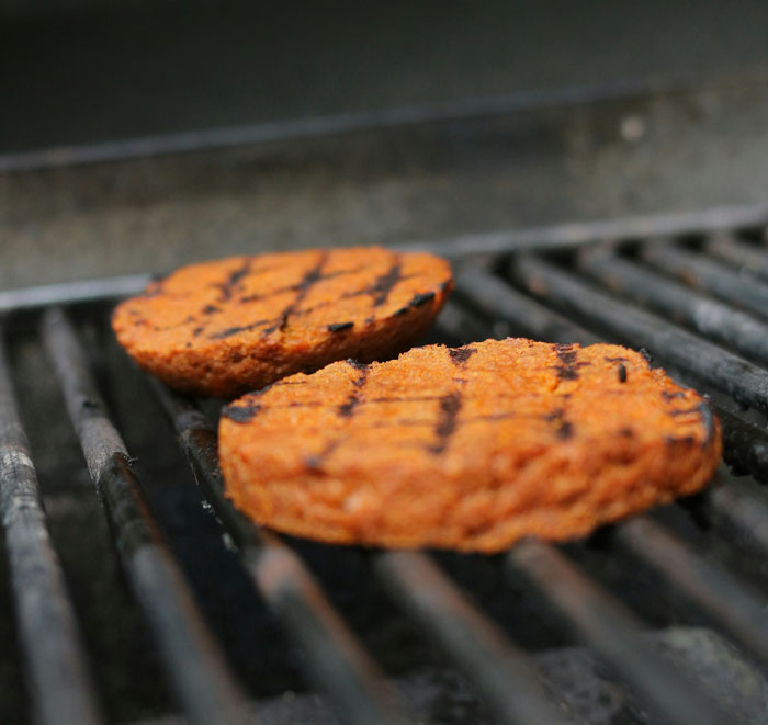 Vegan burgers grilling on a barbecue, highlighting vegan lifestyle at family gatherings. Vegan burgers grilling on a barbecue, highlighting vegan lifestyle at family gatherings.
