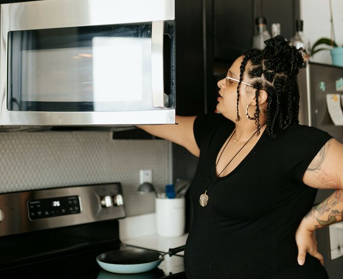 Home chef using a microwave, demonstrating a cooking cheat in a modern kitchen setting.