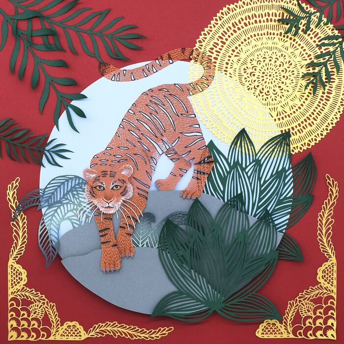 Intricate paper art of a tiger surrounded by foliage and a sun, inspired by nature.