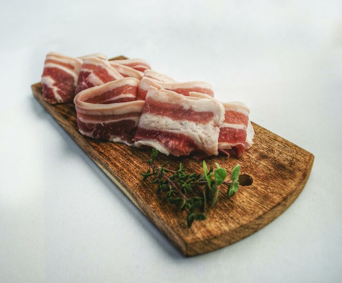 Sliced bacon on a wooden board, highlighting fitness myths about diet and health.